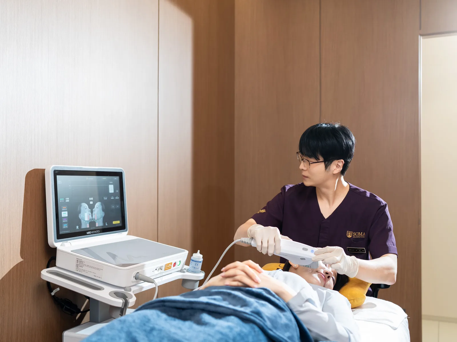 피부과 전문의가 장비 화면을 확인하며 얼굴 시술을 진행하는 장면