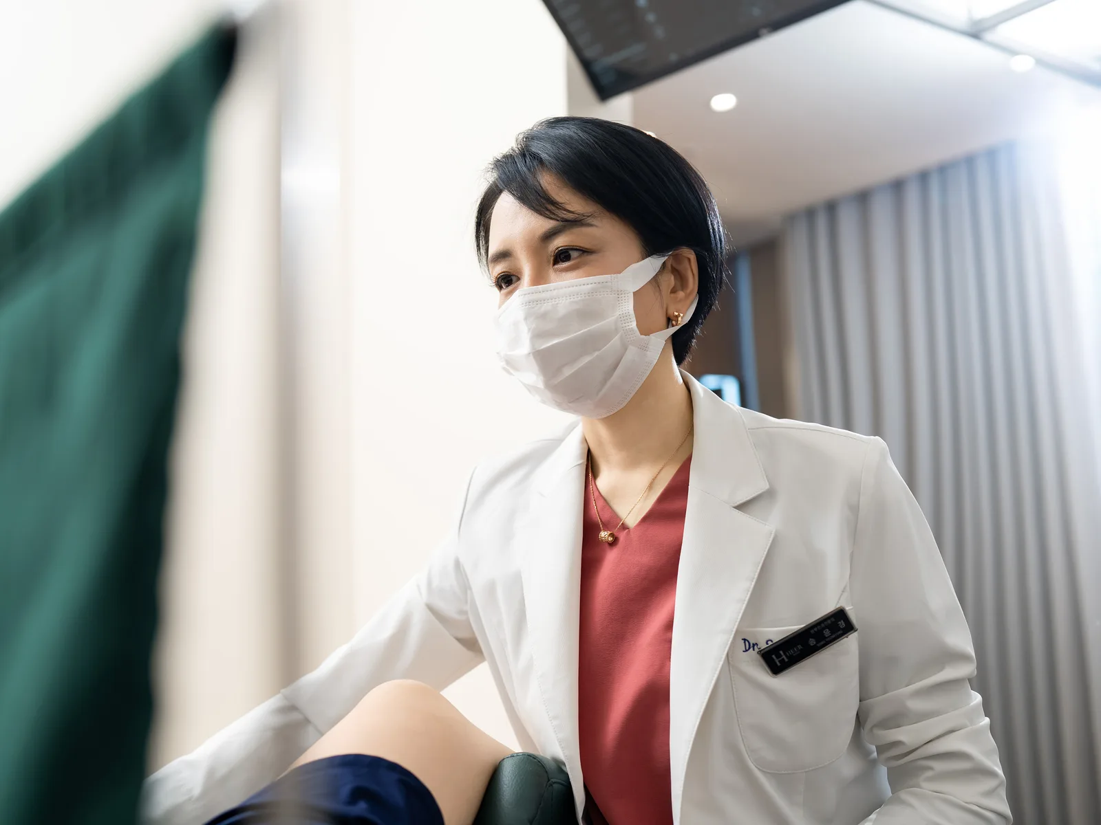 마스크를 쓴 산부인과 전문의가 진료 체어 옆에서 진료하는 장면